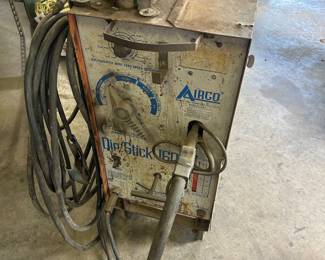 This is an Airco DipStick 160 welder, which is a vintage industrial machine designed for both MIG and stick welding.The unit is constructed on a cart for mobility and includes essential components like a welding gun and ground cable.