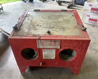 This is a red Clarke sandblast cabinet for removing paint, rust, or debris from small parts.