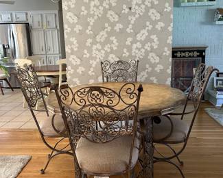 Mediterranean inspired wrought iron dining set pieces, featuring intricate scrolled designs and upholstered seats