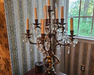 bronze or brass figural candelabra table lamp featuring crystal prisms and a cherub or lady motif.