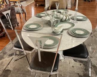 Large table with a sleek top and  transparent acrylic chairs