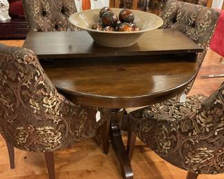 Dark wood round pedestal table paired with four upholstered side chairs