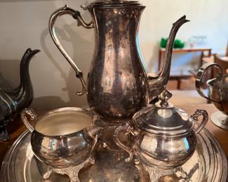 silver-plated four-piece coffee set featuring ornate handles and feet