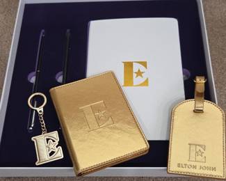 Lot #166 - Elton John Gold Travel Set with Keychain, Luggage Tag, Passport Holder, Notebook & Pens