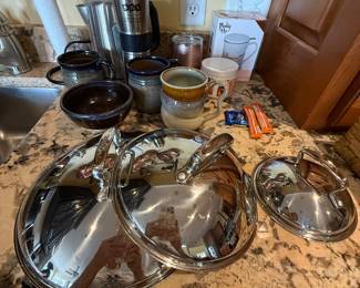 Lids to copper pots and pans hanging on iron rack
