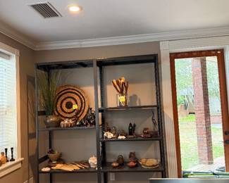Lots of African pottery, wooden items, baskets on large shelf 