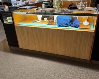 One of a pair of 5-1/2’ showcases with storage cabinets with sliding doors
