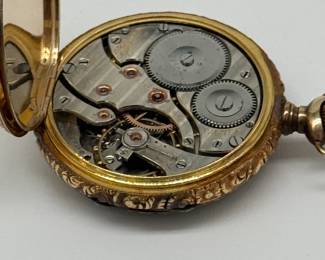 Another view of the 18K yellow gold Gruen pocket watch, late 19th/early 20th century. The face is adorned with intricate tri-color gold (white, rose, and yellow) floral engravings. The watch is housed in an 18K gold case, featuring heavily chased, ornate scrollwork; inscribed inside with “Swiss” and stylized logo for Dietrich Gruen & Sons, and numerals 125758.