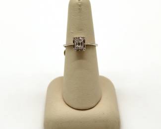 White gold engagement ring featuring an invisible-set baguette and round diamond clusters 