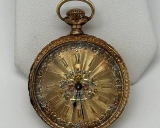 18K yellow gold Gruen pocket watch, late 19th/early 20th century. The face is adorned with intricate tri-color gold (white, rose, and yellow) floral engravings. The watch is housed in an 18K gold case, featuring heavily chased, ornate scrollwork; inscribed inside with “Swiss” and stylized logo for Dietrich Gruen & Sons, and numerals 125758.