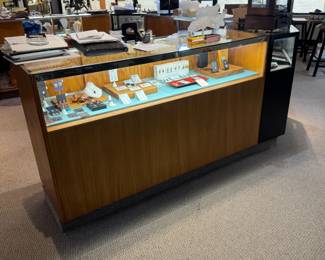 One of a pair of 5-1/2’ showcases with storage cabinets with sliding doors