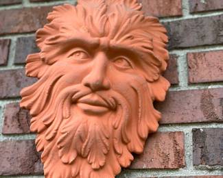 Terracotta-colored Green Man stone garden wall plaque.
