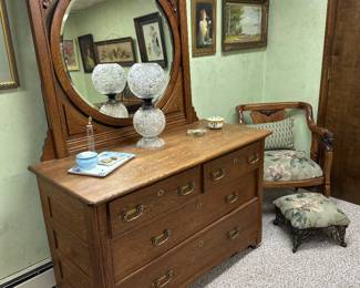 This is a vintage Victorian-style golden oak dresser featuring a large, ornate carved swivel mirror.