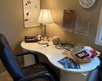 Another desk with side file cabinet and office chair, lamp and office supplies, wall racks and clock