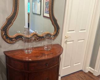 Large black and gold mirror above Ethan Allen demi-lune cabinet