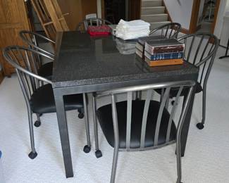 5-piece modern industrial-style dining set featuring a dark granite-topped table and four metal-framed chairs with upholstered seats and caster wheels.