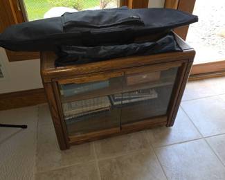This is a vintage wood stereo cabinet with glass doors and wheels.