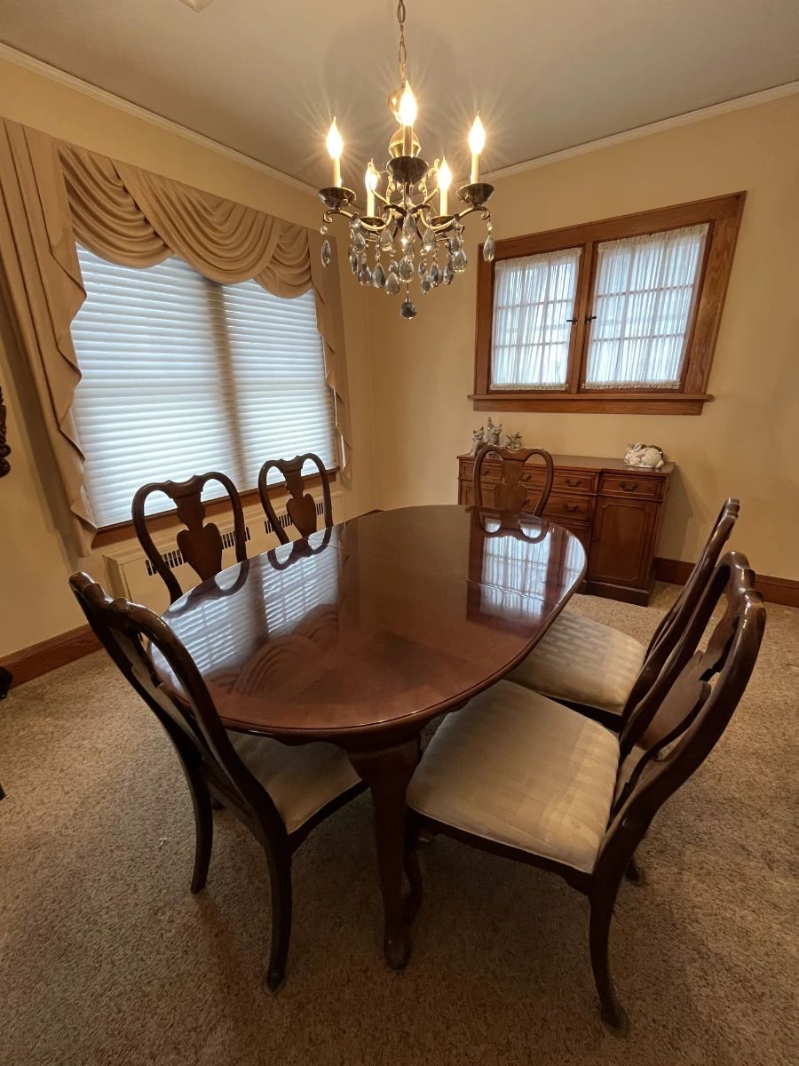 Queen Anne–style dining table with 8 matching chairs, complete with a fitted protective cover. Crystal chandelier, serving buffet table and more. 