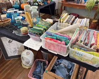 Lots of colored cotton fabrics, fat quarters, jean material, jean pockets, books, vintage blue glass, fan, art