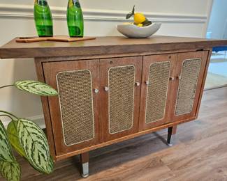 $75 This is a Mid-Century Modern rattan and wood sideboard credenza featuring four doors and metal legs. Some damage rattan on far right door. Laminated top.  
