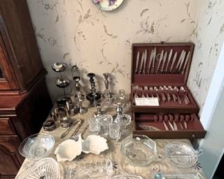 Table is full of silverplate, glass and ceramic items.