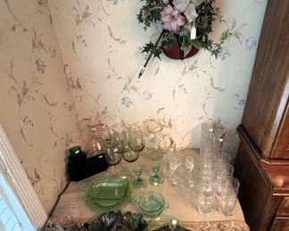 Table has glassware, green depression glass and hand painted china plates.