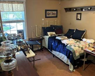 Bedroom is full with picture frames, office supplies and bedding.