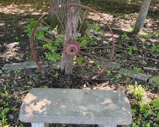 Concrete bench and old wagon wheel.
