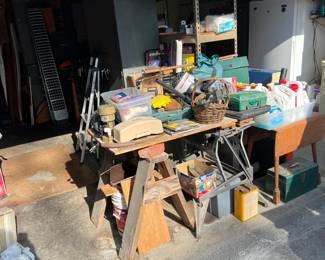 Hidden under the plywood tabletop and adjacent to the sawhorse, is one of those small, portable workbenches.