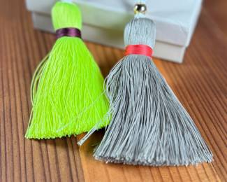 This lot features a pair of India Hicks Junkanoo tassels for bags, both in excellent condition in an original box.