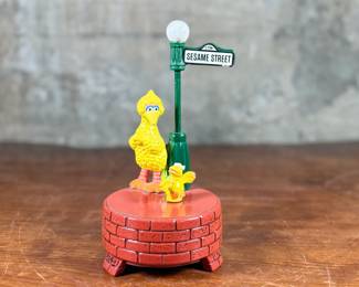 This lot features a 1976 Gorham Sesame Street Big Bird and Little Bird music box. The music box features Big Bird standing next to a “Sesame Street” signpost. It operates using a magnet mechanism that makes the small bird dance on the brick-patterned base. It was produced by the Gift World of Gorham and is in working condition.
