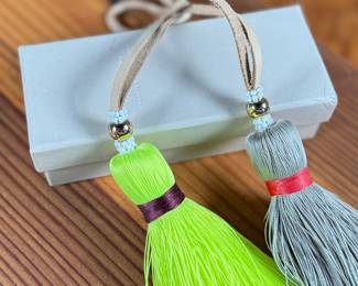 This lot features a pair of India Hicks Junkanoo tassels for bags, both in excellent condition in an original box.