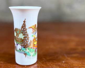 This lot features a vintage 1970s porcelain vase designed by Bjørn Wiinblad for Rosenthal Studio-Linie, featuring a whimsical colorful illustration of a harp player. Measures, 4” H and comes in excellent condition.