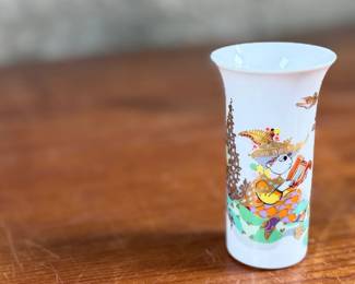 This lot features a vintage 1970s porcelain vase designed by Bjørn Wiinblad for Rosenthal Studio-Linie, featuring a whimsical colorful illustration of a harp player. Measures, 4” H and comes in excellent condition.