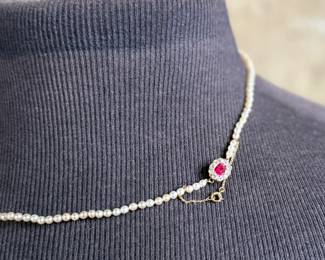 This lot features a stunning Art Deco genuine pearl necklace with a dual-clasp featuring a ruby and genuine diamonds. This necklace measures, 20” with a total approx. weight of 13.81 grams.