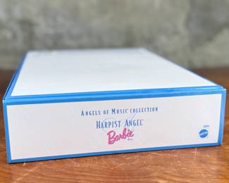 This lot features a Mattel Angels of Music Collection Harpist Angel Barbie Doll, released as a Collector Edition in 1997. This doll is the first in a series titled the “Angels of Music Collection”. The doll features a periwinkle chiffon gown with a butterscotch satin underlay and holds a golden harp. It is designed as a “Collector Edition” and features delicate feather wings. Brand new condition.