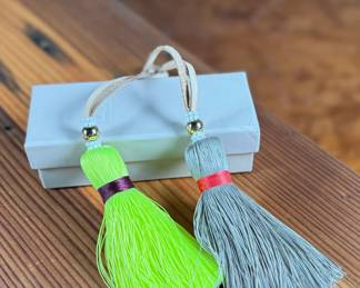 This lot features a pair of India Hicks Junkanoo tassels for bags, both in excellent condition in an original box.