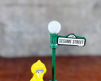 This lot features a 1976 Gorham Sesame Street Big Bird and Little Bird music box. The music box features Big Bird standing next to a “Sesame Street” signpost. It operates using a magnet mechanism that makes the small bird dance on the brick-patterned base. It was produced by the Gift World of Gorham and is in working condition.