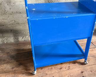 This lot features a two (2) piece wooden book or bar cart on casters with a fold down shelf. This cabinet measures, 65” H x 29.5” W x 19.5” D. Small crack that could be repaired on a caster as shown in photos.