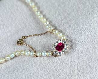 This lot features a stunning Art Deco genuine pearl necklace with a dual-clasp featuring a ruby and genuine diamonds. This necklace measures, 20” with a total approx. weight of 13.81 grams.