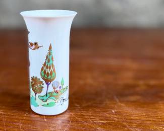 This lot features a vintage 1970s porcelain vase designed by Bjørn Wiinblad for Rosenthal Studio-Linie, featuring a whimsical colorful illustration of a harp player. Measures, 4” H and comes in excellent condition.