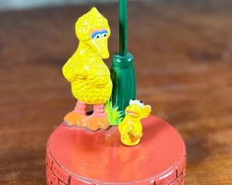 This lot features a 1976 Gorham Sesame Street Big Bird and Little Bird music box. The music box features Big Bird standing next to a “Sesame Street” signpost. It operates using a magnet mechanism that makes the small bird dance on the brick-patterned base. It was produced by the Gift World of Gorham and is in working condition.