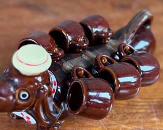 This lot features a vintage dachshund-shaped ceramic decanter set, often referred to as a "drunken dog" liquor flask set. In excellent condition and measures, 5” H x 13” W x 7” D.
