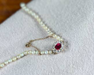 This lot features a stunning Art Deco genuine pearl necklace with a dual-clasp featuring a ruby and genuine diamonds. This necklace measures, 20” with a total approx. weight of 13.81 grams.