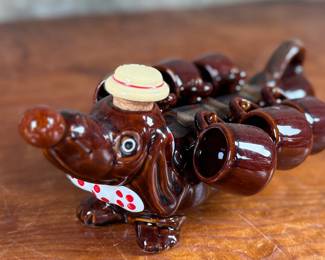 This lot features a vintage dachshund-shaped ceramic decanter set, often referred to as a "drunken dog" liquor flask set. In excellent condition and measures, 5” H x 13” W x 7” D.