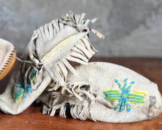 This lot features a pair of what appear to be antique Native American moccasins, consistent with styles produced in the 19th century by Plains tribes.
