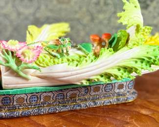 This lot features a Chinese carved and painted vegetable sculpture featuring bok choy, grasshopper, flowers, and more. Carved out of bone, quite delicate and will not be shipped in house.