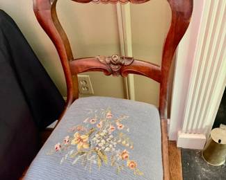 This is a vintage Victorian balloon back side chair featuring carved walnut wood and a floral needlepoint seat