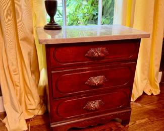 Three-drawer nightstand with a marble top and a cherry wood finish
