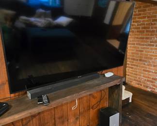 Large television, sound bar and base, and couch table